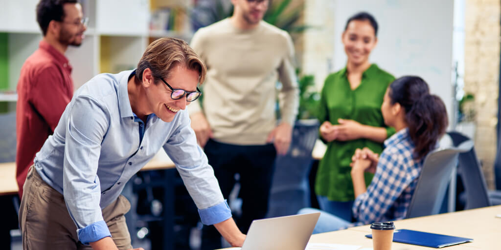 person working on a laptop with the rest of the team in the background